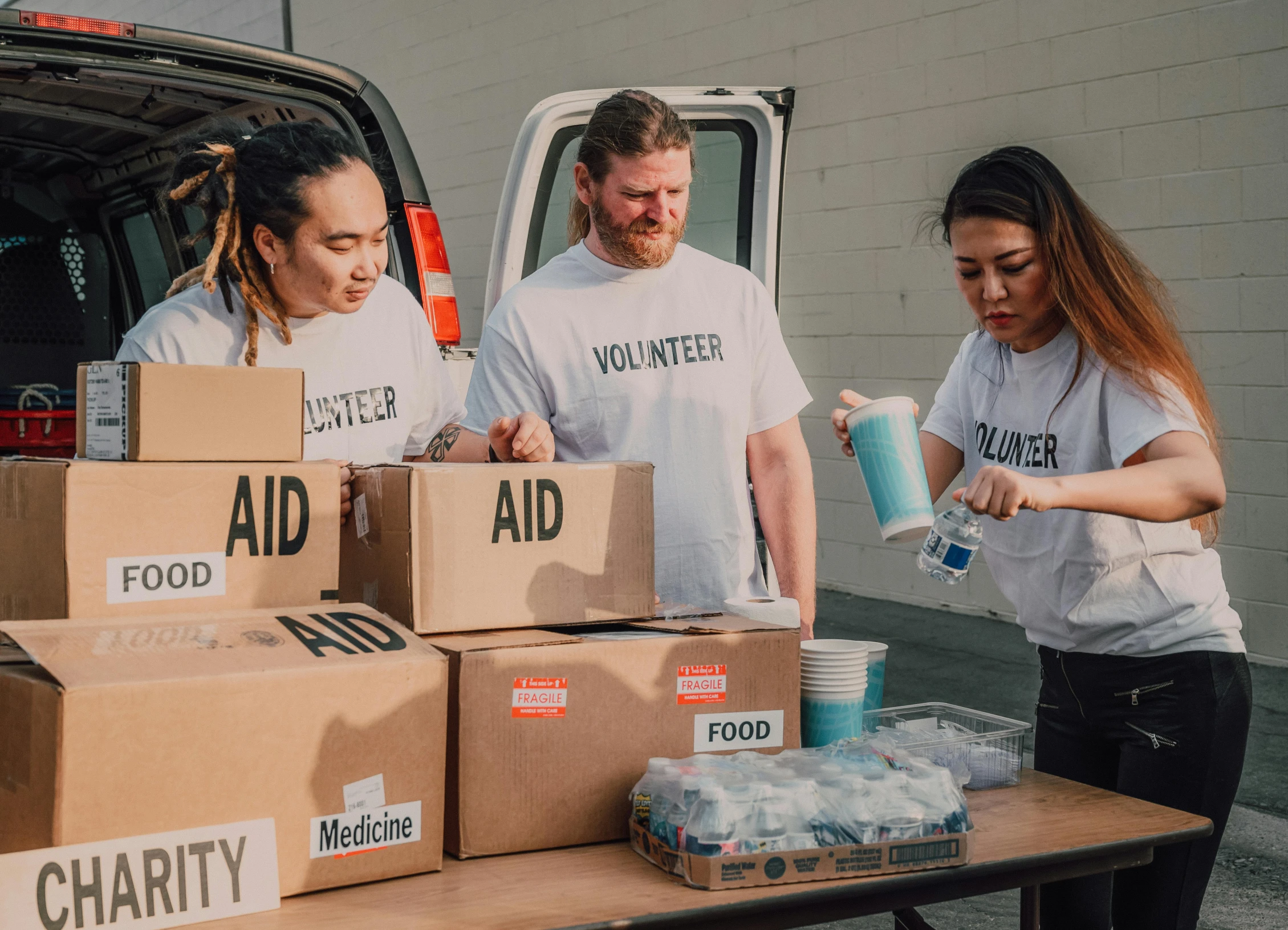 a group of people standing around a table filled with boxes, by Francis Helps, pexels contest winner, first aid kit, wētā fx, hunger, 🚀🌈🤩