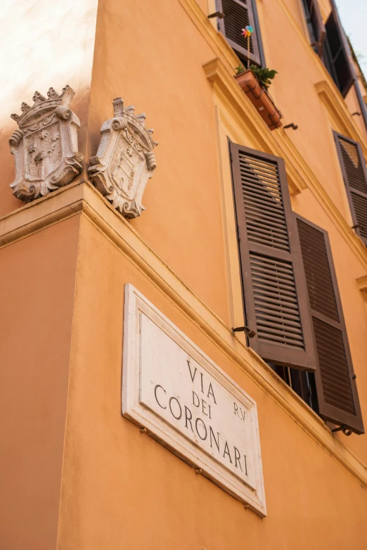 a sign that is on the side of a building, inspired by Giorgio De Vincenzi, large cornicione, apartment, coronation, brown