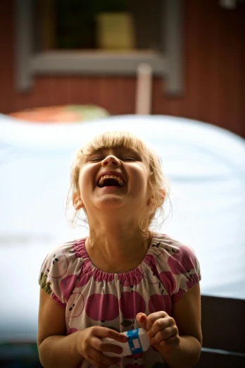 a little girl laughing and holding a toothbrush, by Lee Loughridge, pexels contest winner, incoherents, in a ball pit, square, paul barson, looking upwards