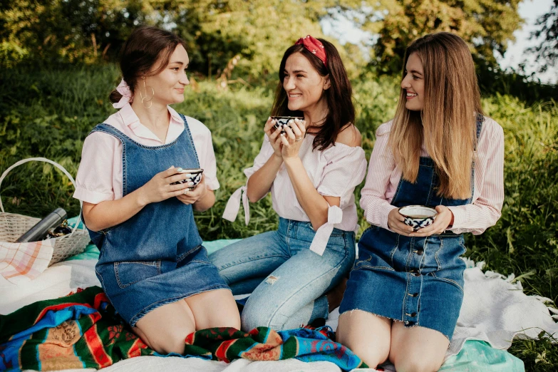 a couple of women sitting on top of a blanket, trending on pexels, blue overalls, tea party, three women, ukrainian national clothes