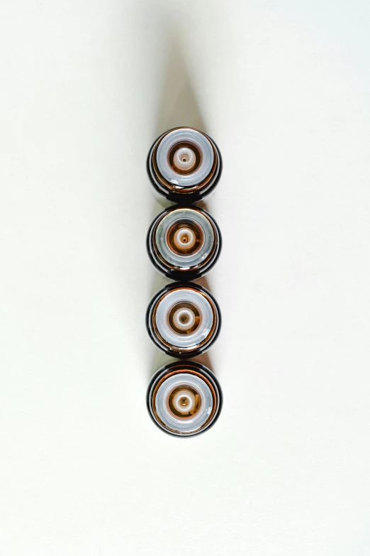 a close up of a metal object on a white surface, a picture, unsplash, op art, vibrant vials, brown, enso, made of glazed