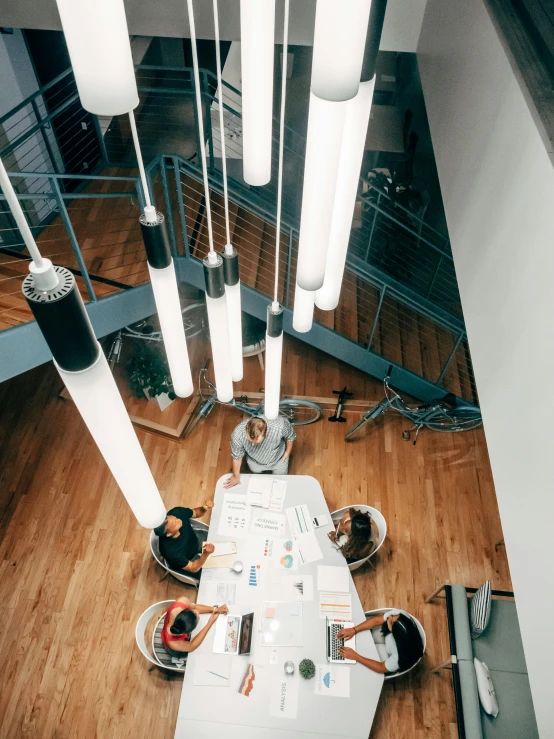 a group of people sitting around a long table, pexels contest winner, light and space, high angle view, cables hanging from ceiling, low quality photo, thumbnail