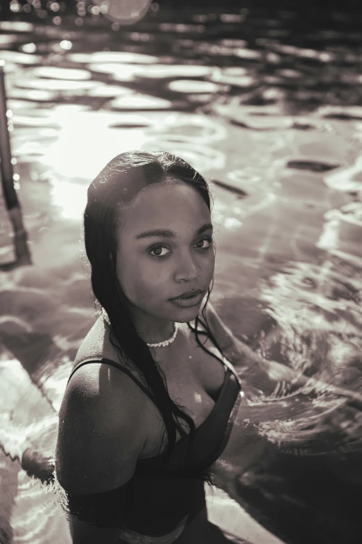 a black and white photo of a woman in a pool, vanessa morgan, sundown, young black woman, she is facing the camera