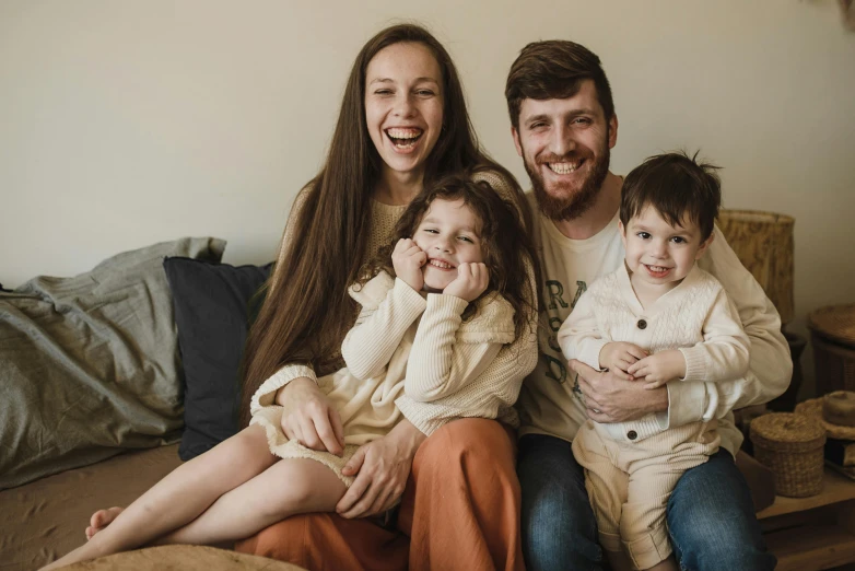 a man sitting on top of a couch next to a woman and two children, a portrait, pexels, avatar image, australian, romanian, happy and beautiful