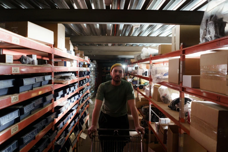 a man pushing a shopping cart through a warehouse, a portrait, reddit, museum quality photo, spare parts, lachlan bailey, in a basement