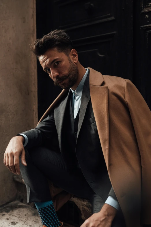 a man in a suit and tie leaning against a wall, inspired by Francesco Furini, trending on pexels, renaissance, brown tuffle coat, bearded beautiful man, at a fashion shoot, thumbnail