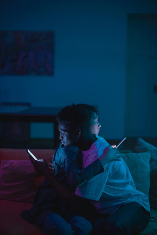 a couple of kids sitting on top of a bed, pexels, happening, glowing screens, thin glowing devices, muted lights, multicoloured