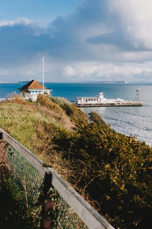 a train on a track next to a body of water, by Julian Allen, unsplash, seaside victorian building, panorama distant view, lighthouse, high quality image”