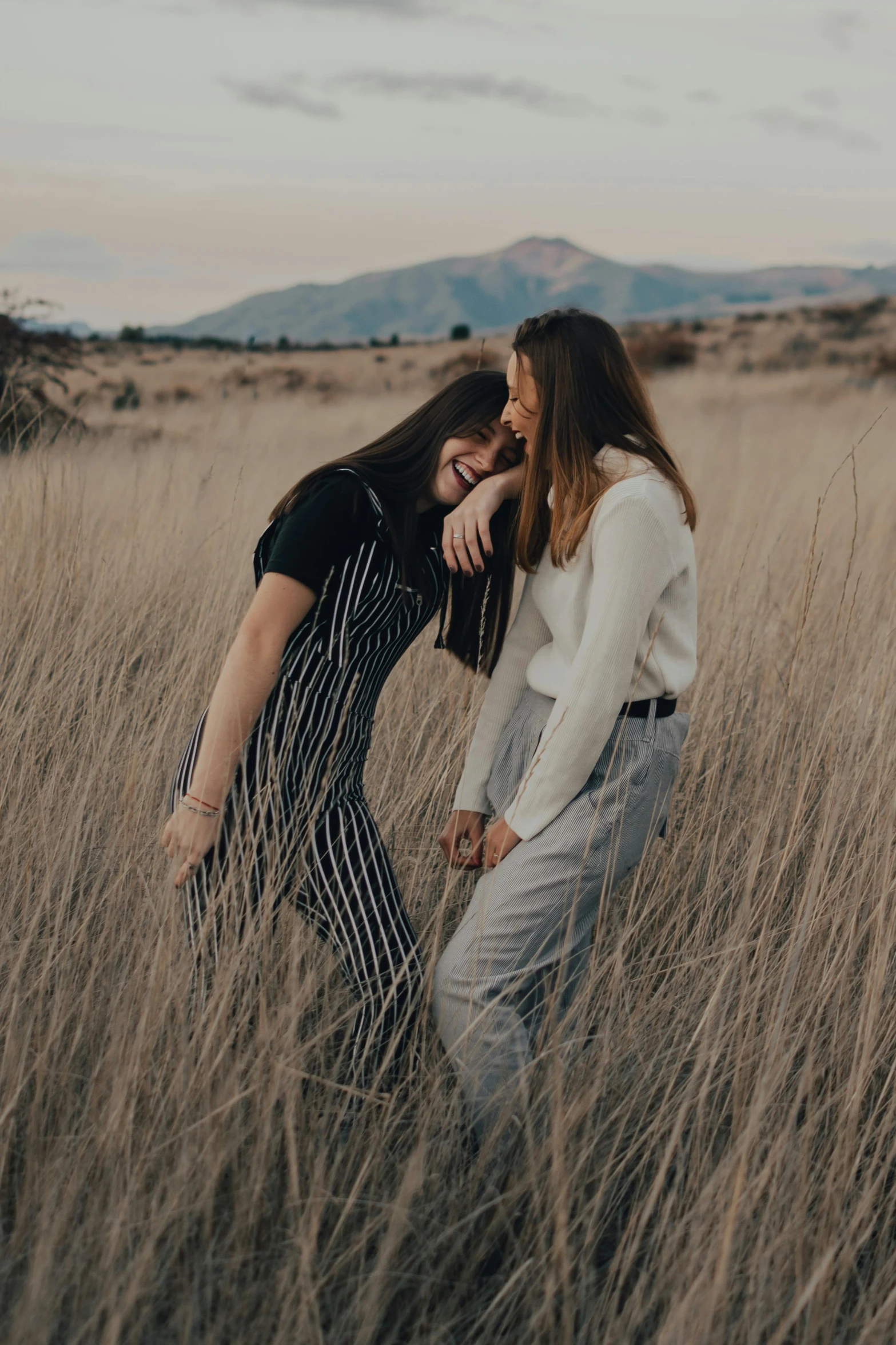 two women laughing in a field of tall grass, trending on pexels, romanticism, standing in a barren field, making out, friends, instagram photo