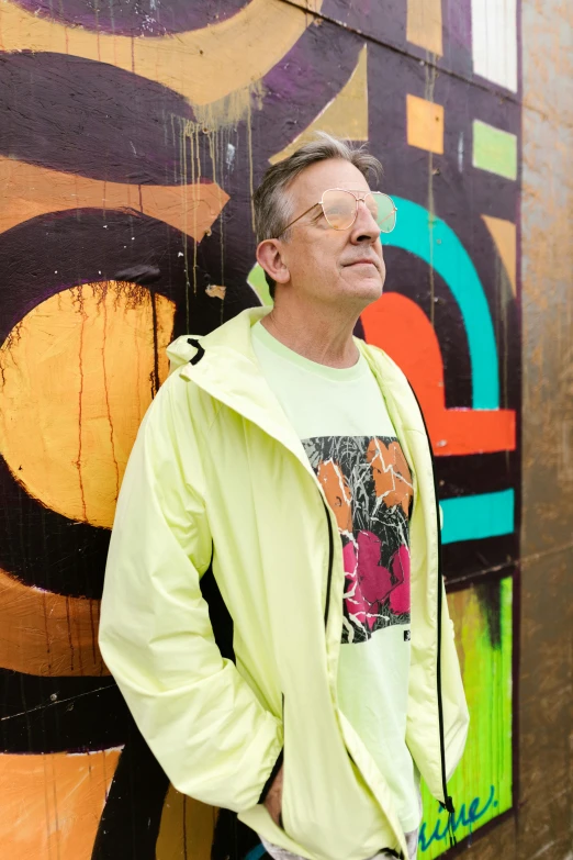 a man standing in front of a graffiti covered wall, an album cover, inspired by Jan de Baen, graffiti, wearing hi vis clothing, craig russell, william gibson, vacation photo