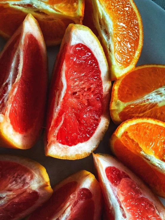 a white plate topped with slices of grapefruit, by Carey Morris, trending on pexels, dark oranges reds and yellows, soft grey and red natural light, zoomed in, an orgy of colorful