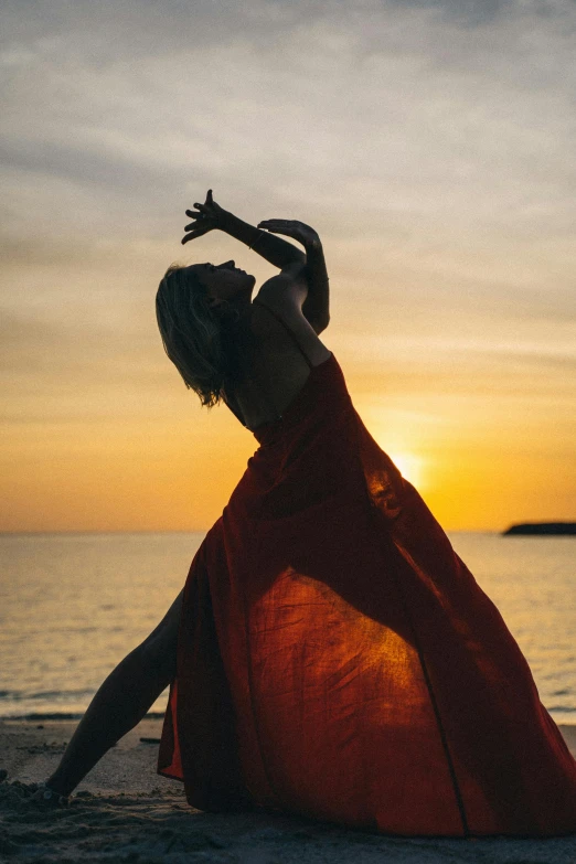 a woman in a red dress on the beach, pexels contest winner, renaissance, dynamic dancing pose, sun setting, draped in flowing fabric, instagram post