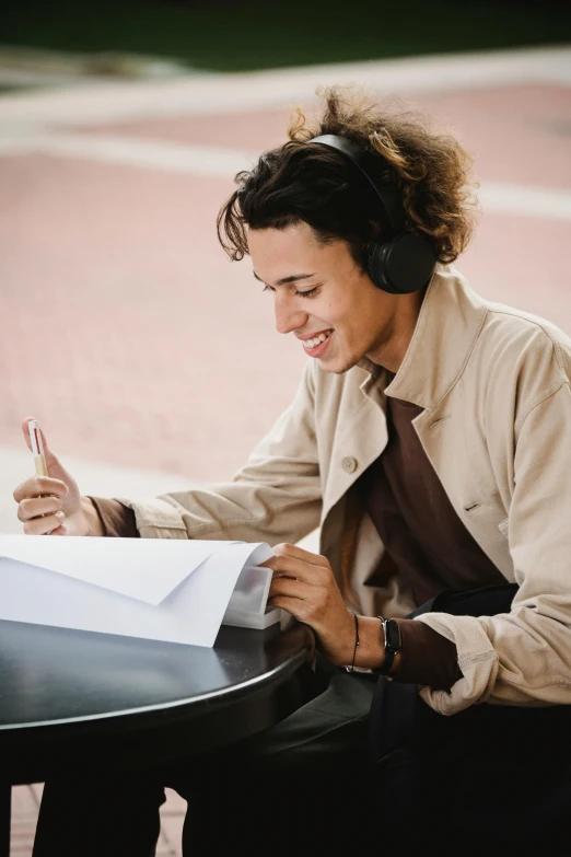 a man sitting at a table with a piece of paper, pexels contest winner, academic art, wearing headphones, smiling male, highly stylized, thumbnail