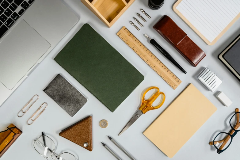 a white table topped with lots of office supplies, a still life, inspired by Benjamin Franklin, trending on pexels, academic art, green and brown clothes, yellow and charcoal leather, asset on grey background, rectangle