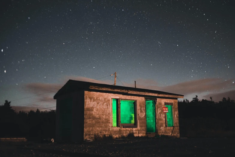 a small building sitting in the middle of a field, an album cover, unsplash contest winner, magical realism, very dark with green lights, northern star at night, green light coming from window, green bright red