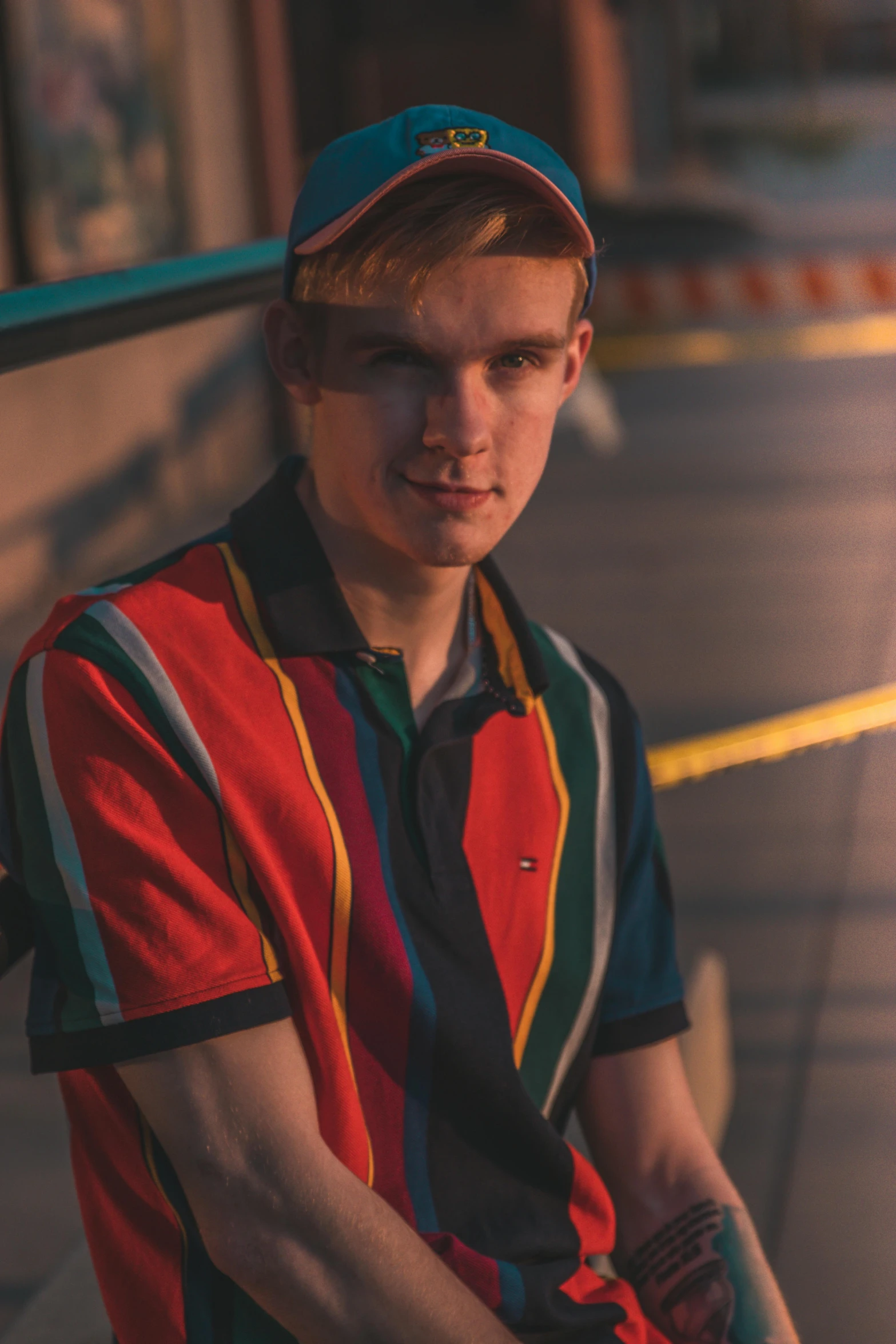 a young man sitting on a bench wearing a baseball cap, an album cover, by Jacob Toorenvliet, unsplash, renaissance, wearing polo shirt, multicolored, vitalik buterin, standing in a dimly lit room