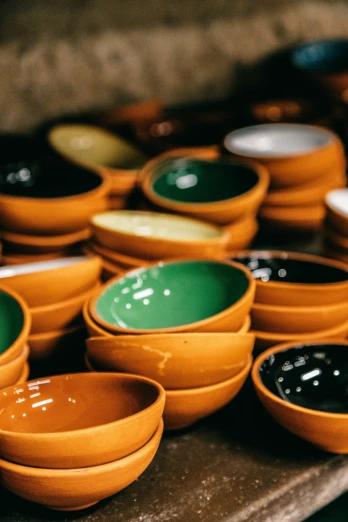 a bunch of bowls sitting on top of a wooden table, inside an arabian market bazaar, black and orange colour palette, green, honey