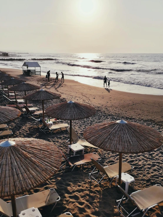 a beach filled with lots of chairs and umbrellas, golden hour”, greek setting, profile image, walking down