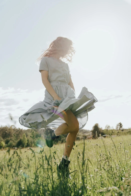 a woman standing on top of a lush green field, twirling, light grey, item, lifestyle