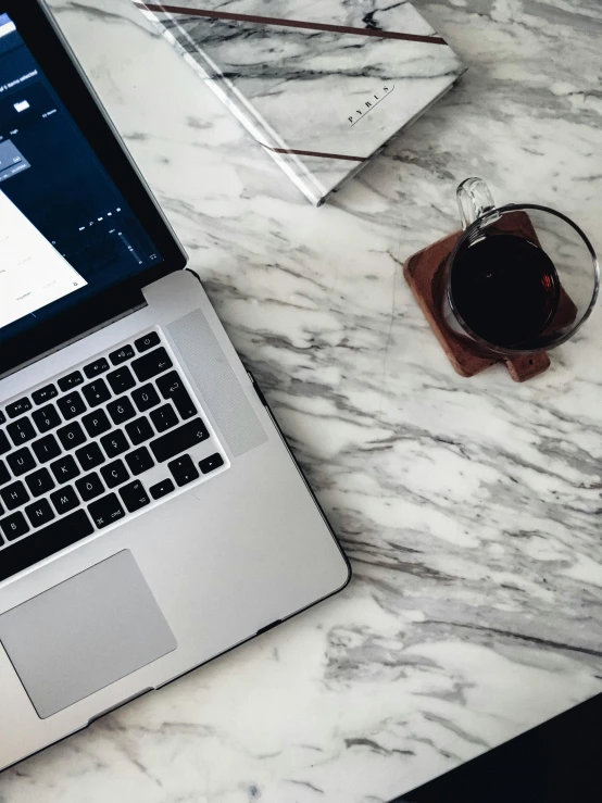 a laptop computer sitting on top of a marble table, instagram picture, dwell, black marble, sitting on a mocha-colored table