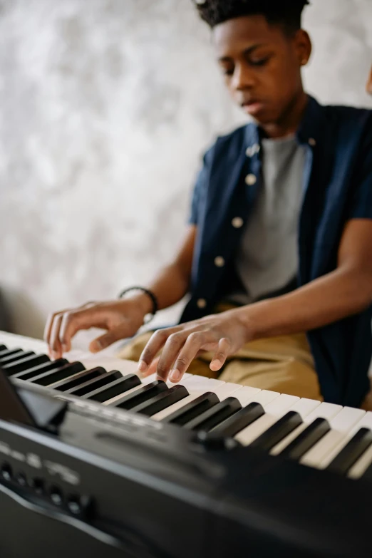 a young man sitting in front of a keyboard, trending on pexels, musicians playing instruments, 💣 💥💣 💥, instagram post, getty images