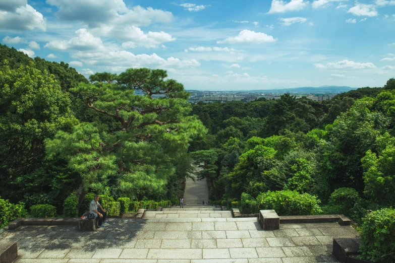 a person sitting on a bench in the middle of a park, inspired by Sesshū Tōyō, unsplash contest winner, sōsaku hanga, palace on top of the hill, with matsu pine trees, green terrace, instagram photo