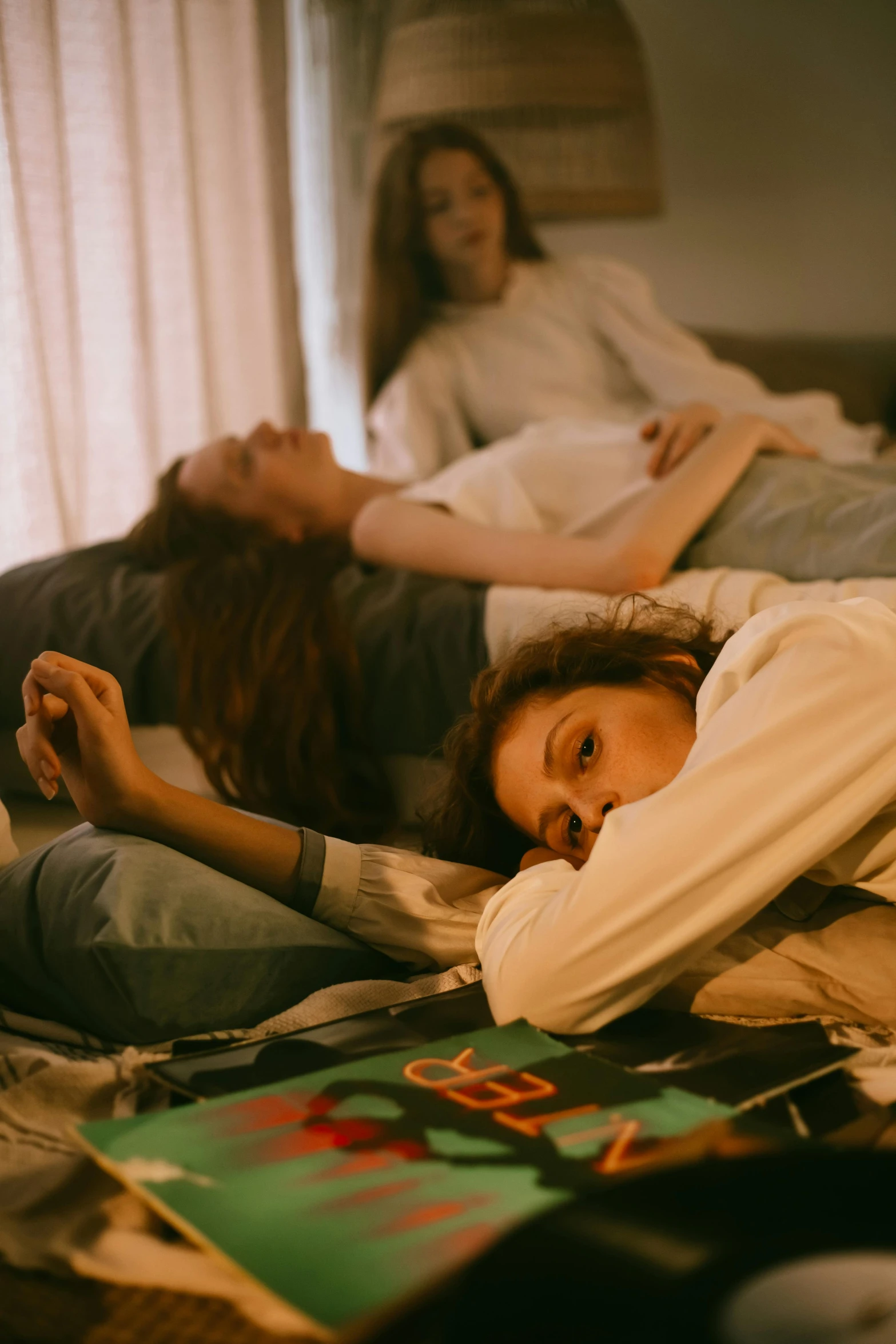 a group of people laying on top of a bed, inspired by Nan Goldin, trending on pexels, three women, sad look, lesbian, teenage