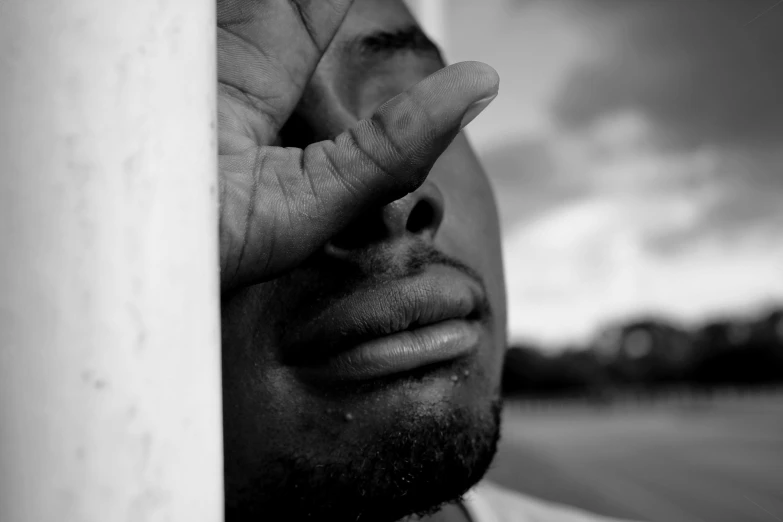 a black and white photo of a man holding his hand up to his face, pexels contest winner, visual art, african american, & the eyes & mouth are closed, tear drop, harsh sunlight