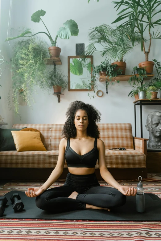 a woman sitting on a yoga mat in a living room, a statue, trending on pexels, paradise garden massage, black young woman, hear no evil, low quality photo