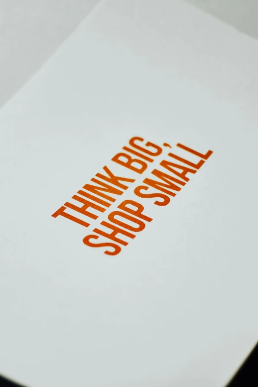 a piece of paper with the words think big shop small on it, a screenprint, white and orange, detail shot, shops, embossed