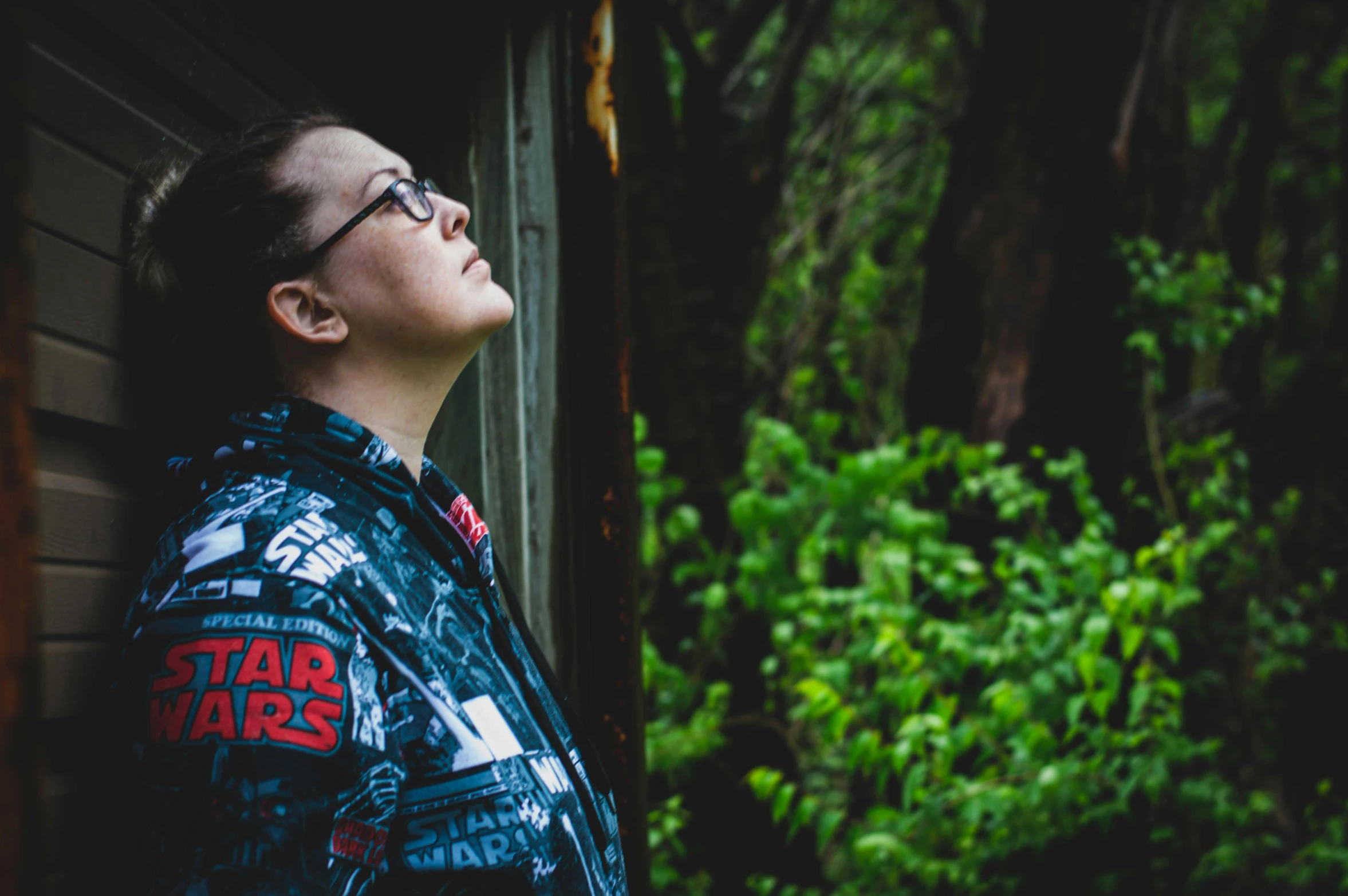 a man with glasses standing in front of a building, inspired by Sōtarō Yasui, unsplash, star wars themed, woman in a dark forest, looking upwards, profile image