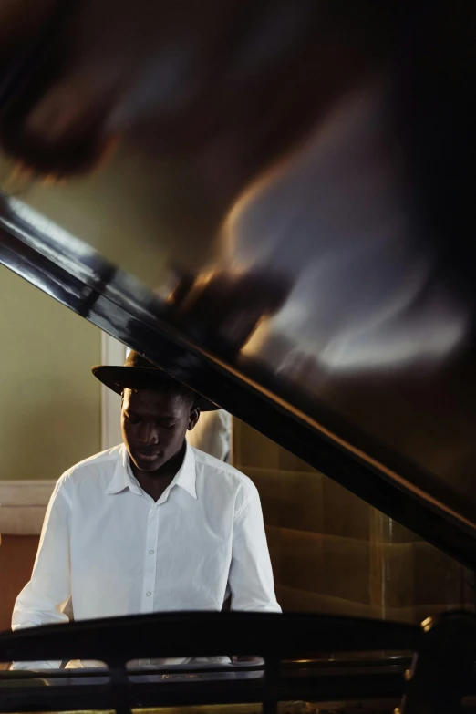 a man in a hat playing a piano, an album cover, inspired by Gordon Parks, unsplash, adut akech, staircase, summer light, ignant