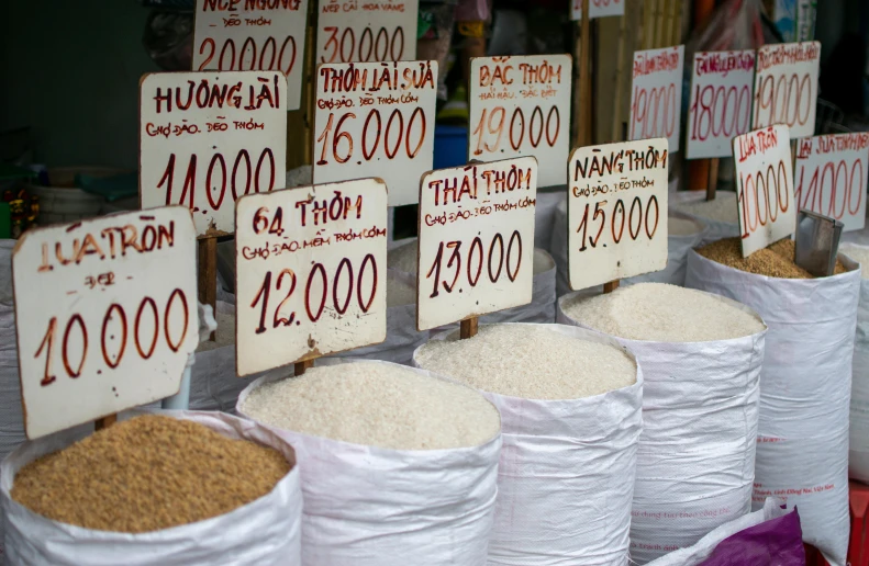 a bunch of bags of rice sitting on top of a table, a photo, by Daniel Lieske, trending on unsplash, dau-al-set, square, market stalls, ao dai, signboards