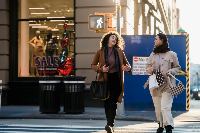 a couple of women walking across a street, by Douglas Shuler, pexels, new york times, brown, casually dressed, advertising