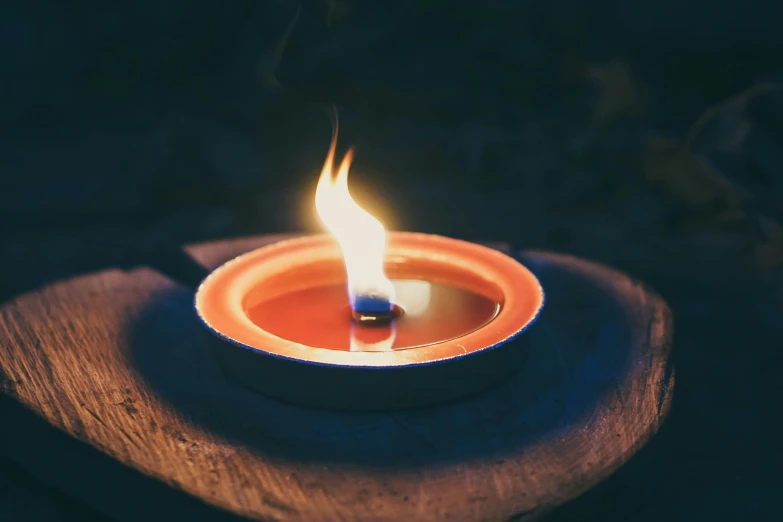 a lit candle sitting on top of a piece of wood, unsplash, fire pit, made of glowing wax and ceramic, warm coloured, on blue fire