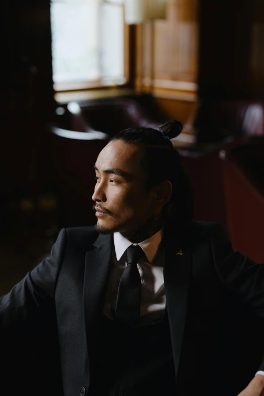 a man in a suit sitting at a table, a portrait, inspired by Li Tiefu, trending on unsplash, robert sheehan, joe taslim, androgynous person, sitting at the bar