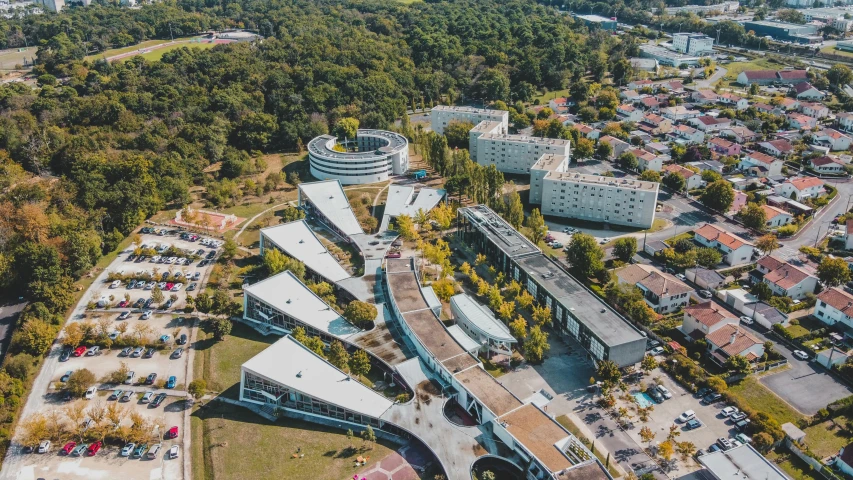 an aerial view of a campus surrounded by trees, by Adam Marczyński, pexels contest winner, renaissance, futuristic france, midcentury modern, curvy build, on a bright day