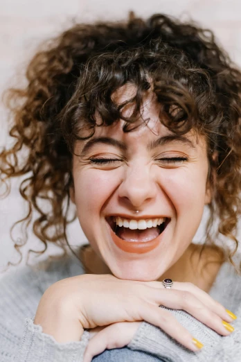 a woman laughing with her hands on her chest, trending on pexels, renaissance, curly bangs and ponytail, rebecca sugar, close up portrait of woman, symmetrical face happy