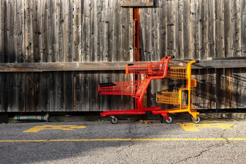 a row of shopping carts sitting in front of a wooden fence, a picture, by Jan Rustem, postminimalism, dark oranges reds and yellows, square, toronto, getting groceries