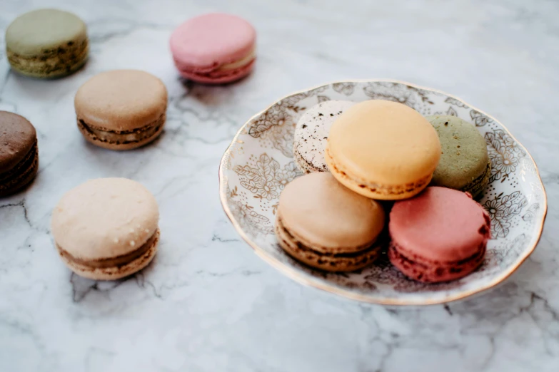 a plate of macarons sitting on top of a table, by Emma Andijewska, trending on pexels, visual art, muted colours 8 k, thumbnail, small, desserts