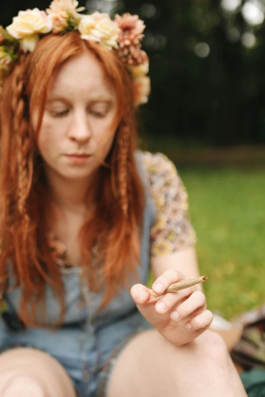 a woman sitting on a blanket with a flower crown on her head, inspired by Mary Jane Begin, unsplash, renaissance, hand holding cigarette, ( redhead, gardening, resin