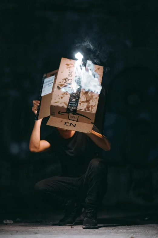 a man sitting on the ground with a box on his head, by Niko Henrichon, pexels contest winner, conceptual art, muzzle flash, discord profile picture, made of cardboard, vapor