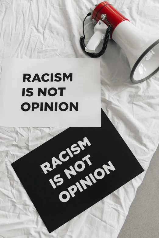 a sign sitting on top of a bed next to a megaphone, a black and white photo, by Arabella Rankin, trending on unsplash, neoism, with brown skin, oppression, paul barson, coffee stain on napkin