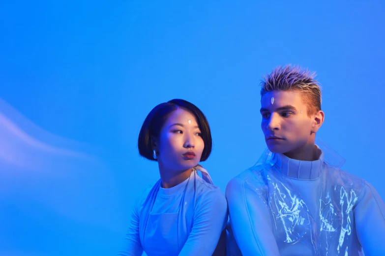 a man and a woman sitting next to each other, an album cover, inspired by Gao Cen, unsplash, neoism, blue lighting, people with mohawks, asian man, blue bioluminescent plastics