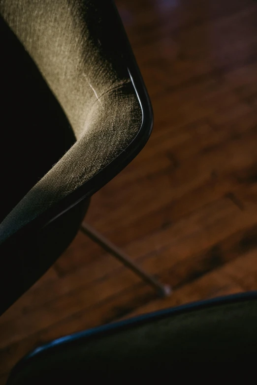 a black chair sitting on top of a hard wood floor, by Adam Chmielowski, trending on unsplash, modernism, muted green, detail shots, dwell, muted browns