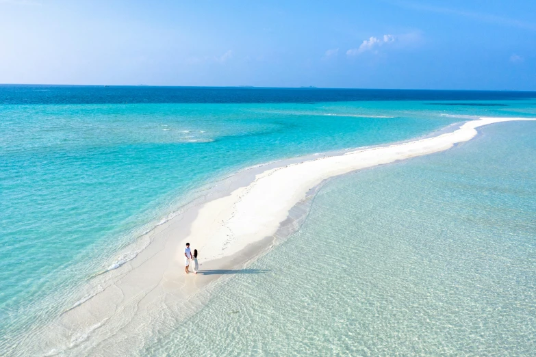 a couple of people standing on top of a sandy beach, light blue water, the ocean, birdeye, white beaches