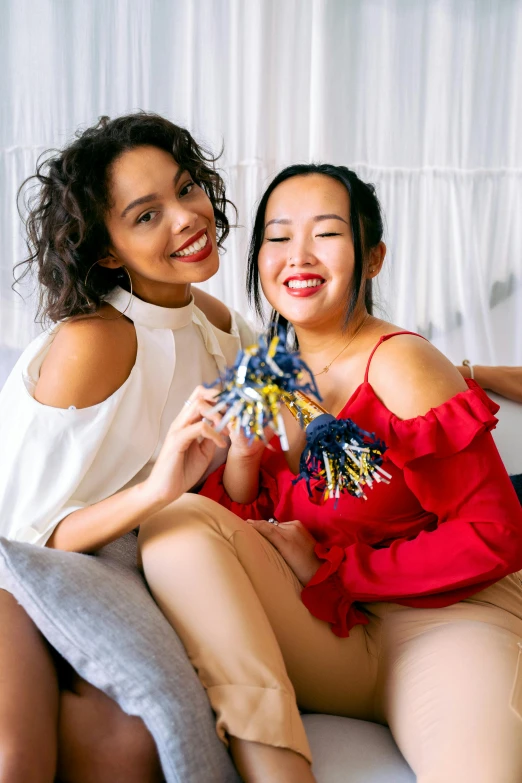 a couple of women sitting on top of a couch, trending on pexels, ruffles tassels and ribbons, asian descent, navy, toys