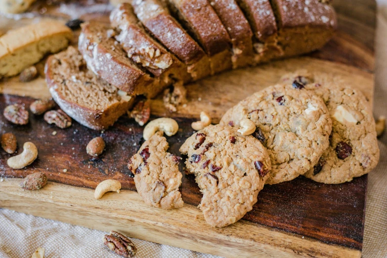 a wooden cutting board topped with cookies and nuts, renaissance, teeth between bread and patty, thumbnail, up close shot, brown bread with sliced salo