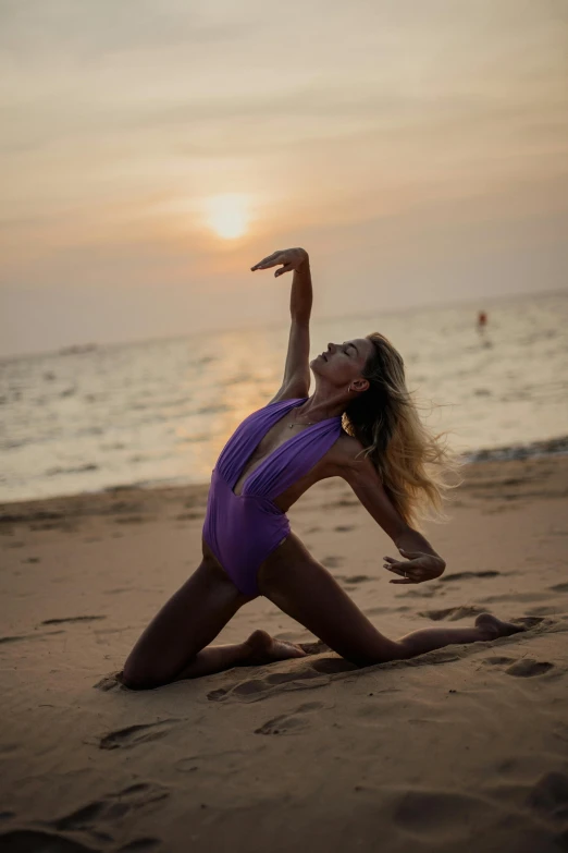 a woman is doing a yoga pose on the beach, by Julian Allen, arabesque, bodysuit, at purple sunset, doing a sassy pose, wearing leotard