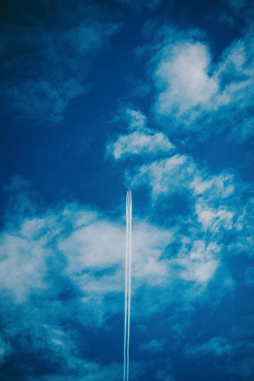 a jet flying through a cloudy blue sky, pexels contest winner, minimalism, streaks, tall, really long, high angle